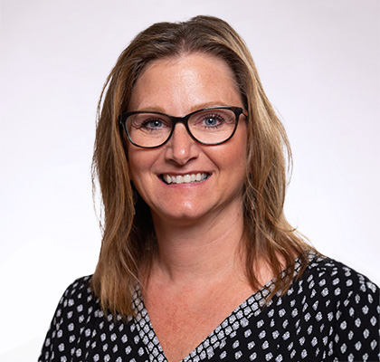 Headshot of Christina Killen, a woman with glasses, blonde hair and a patterned black blouse