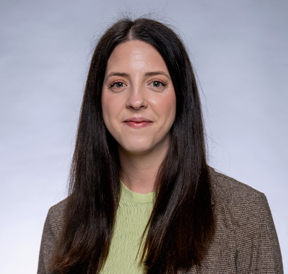 Headshot of Christine Bretschneider-Fries, a young woman with long dark brown hair wearing a light green and tan shirt and blazer