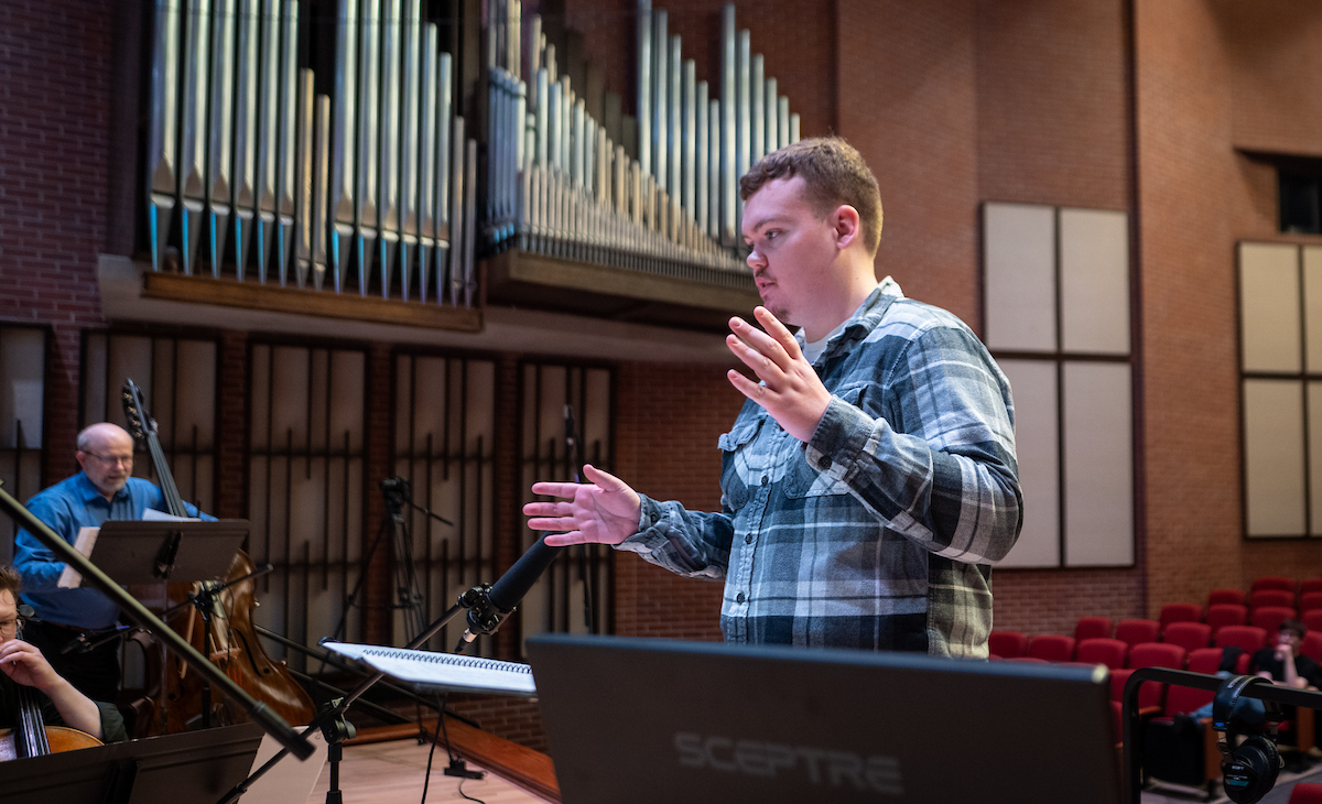 a male choir director leads a symphony orchestra