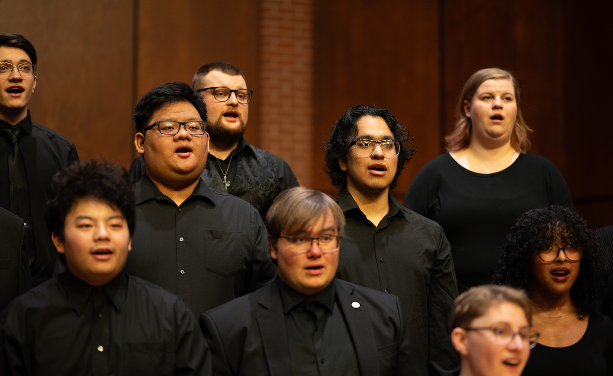 People dressed in black clothing sing with a choir