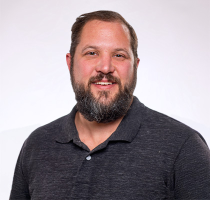 Headshot of Dan Waletzko, a man with brown hair wearing a black polo shirt