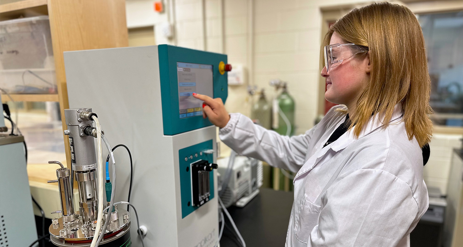 A female student configures a machine in the bioprocessing lab