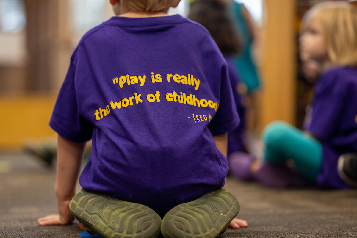 The back of a purple tshirt says "Play is really the work of childhood" in purple font