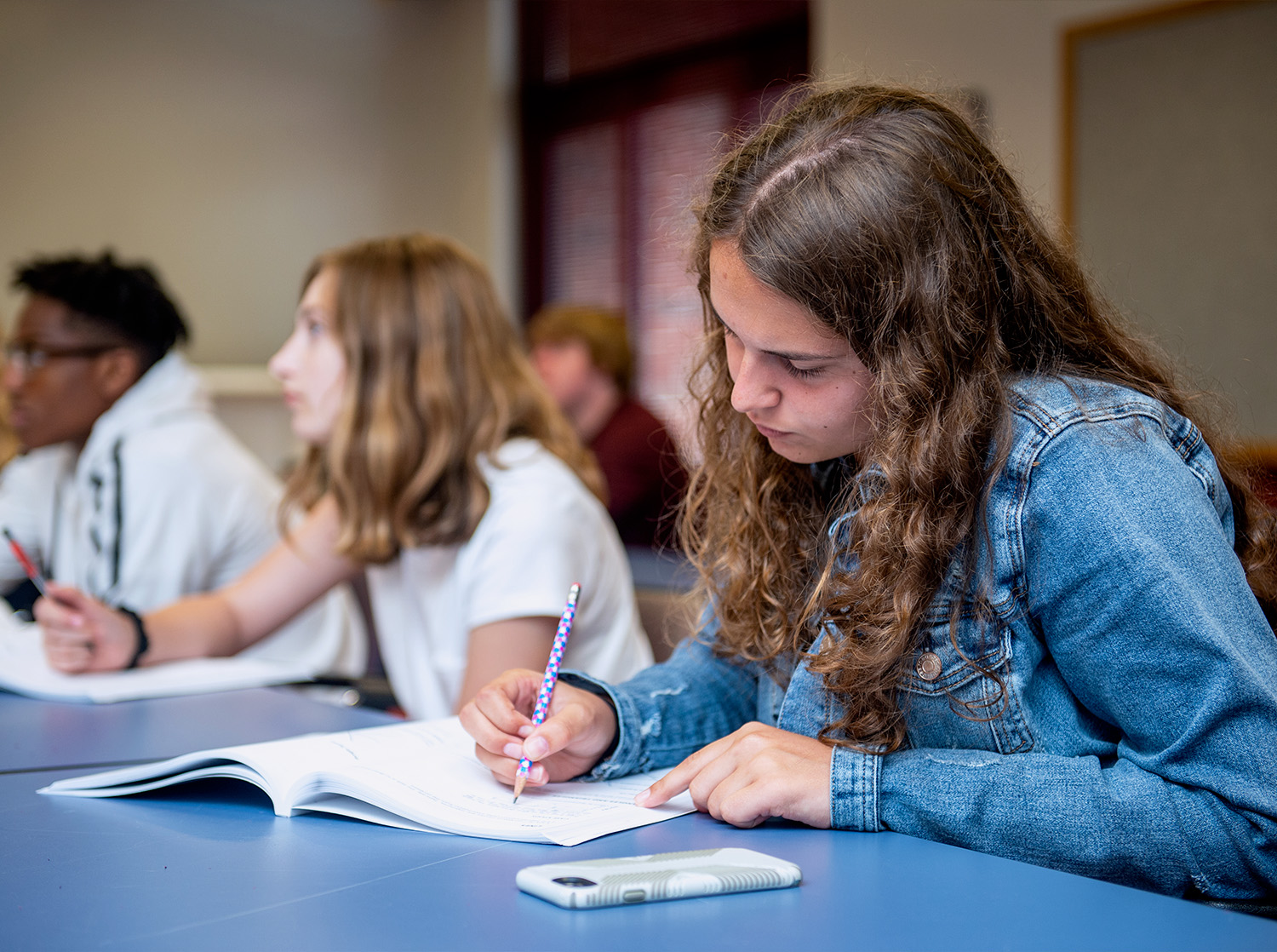 A female student taking a written test alongside other students