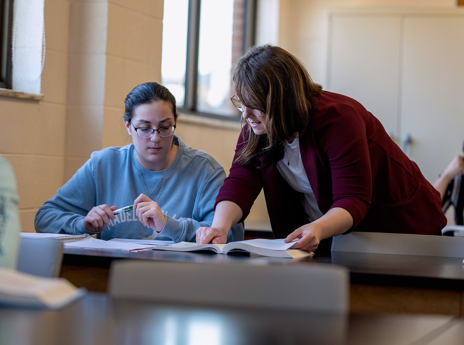 A female professor helps a female student during class.