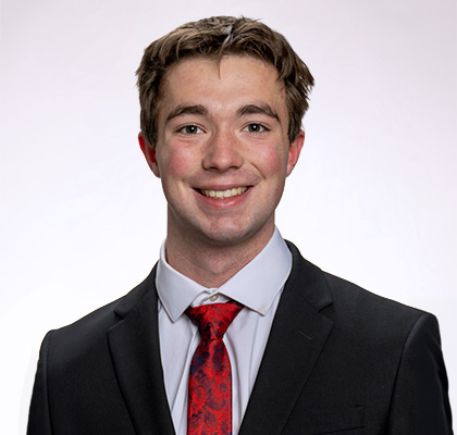 Headshot of Gavin Peterson, a male student wearing a black suit jacket with a red tie