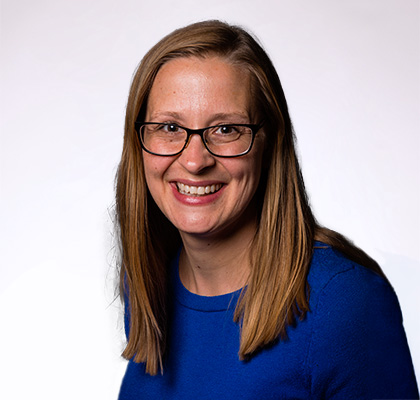 Headshot of Heather Sumner Davis, a woman with glasses and blonde hair wearing a bright blue sweater