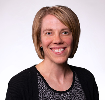 Headshot of Holly Dolliver, a woman with short blonde hair and a black blouse and cardigan