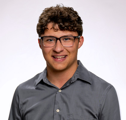 Headshot of Hunter Vlcek, a male student wearing black rim glasses and a dark grey button up
