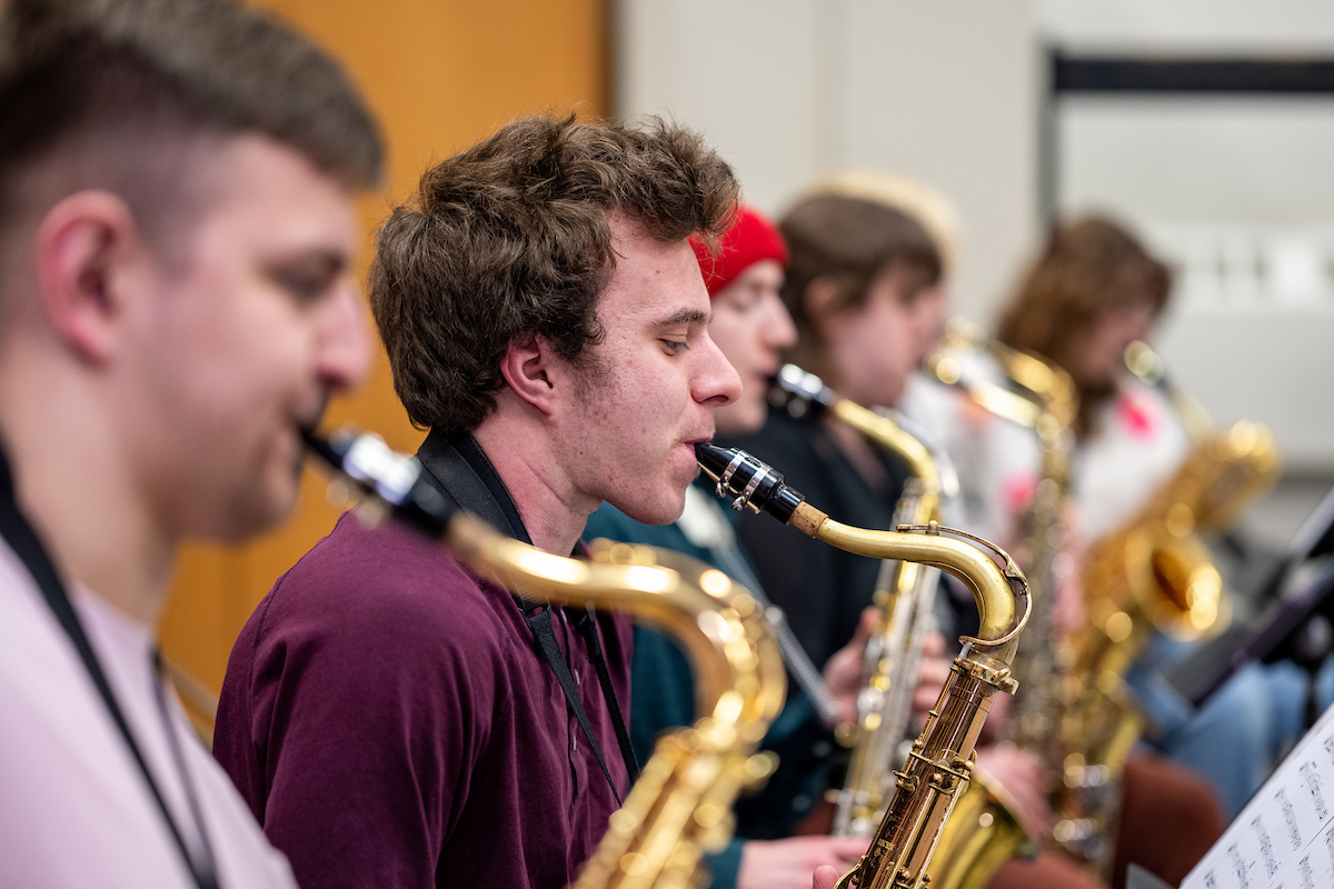 five people are playing saxophones
