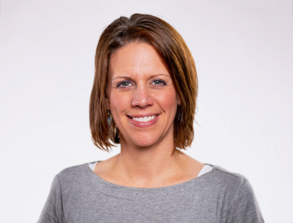 Headshot of Jennifer Herink. A woman with short brown hair and a gray long sleeve shirt