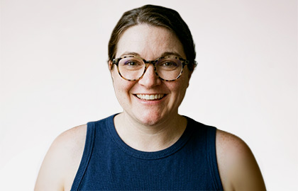 Headshot of Jessi Mularky, a woman with brown hair in a bun and dark blue tank top