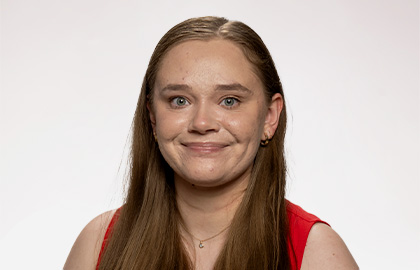 Headshot of Katelyn Pearson, a young woman with long brown hair with a bright red tank top