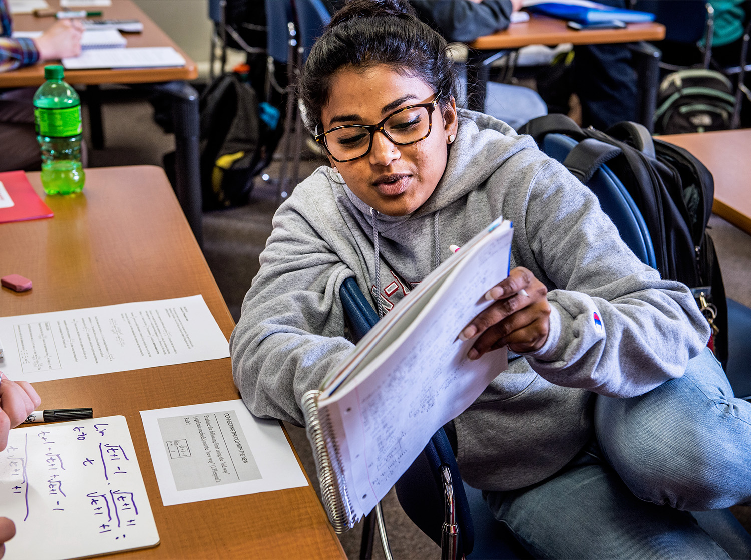 A female student point to a line in their notebook to show to another student during class