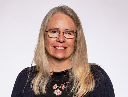 Headshot of Michelle Klechefski. A woman with blonde/gray hair and a flower print blouse