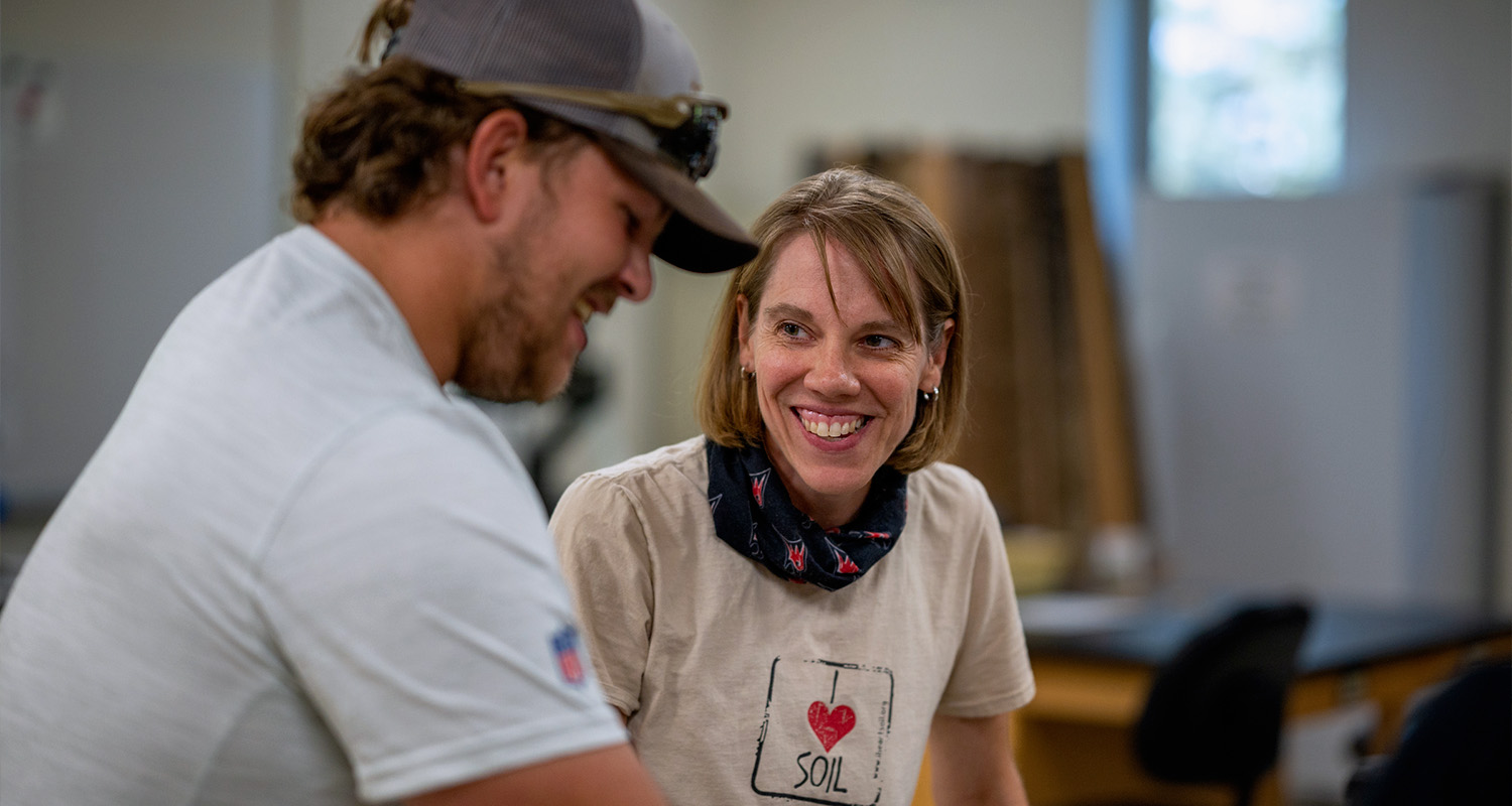 A professor smiles at a student during a lab