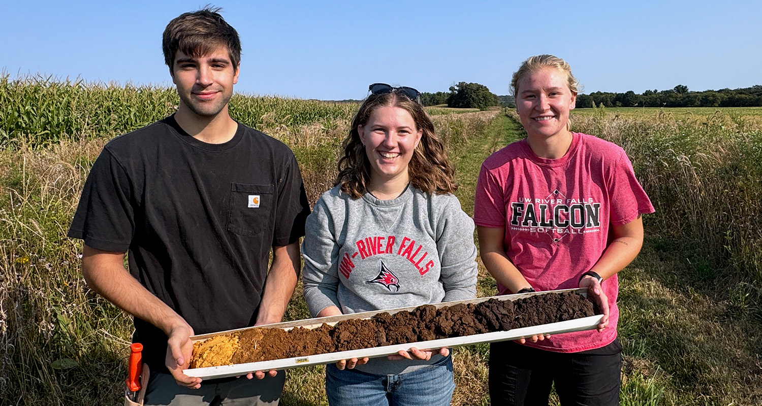 Three students hold a container with dirt samples