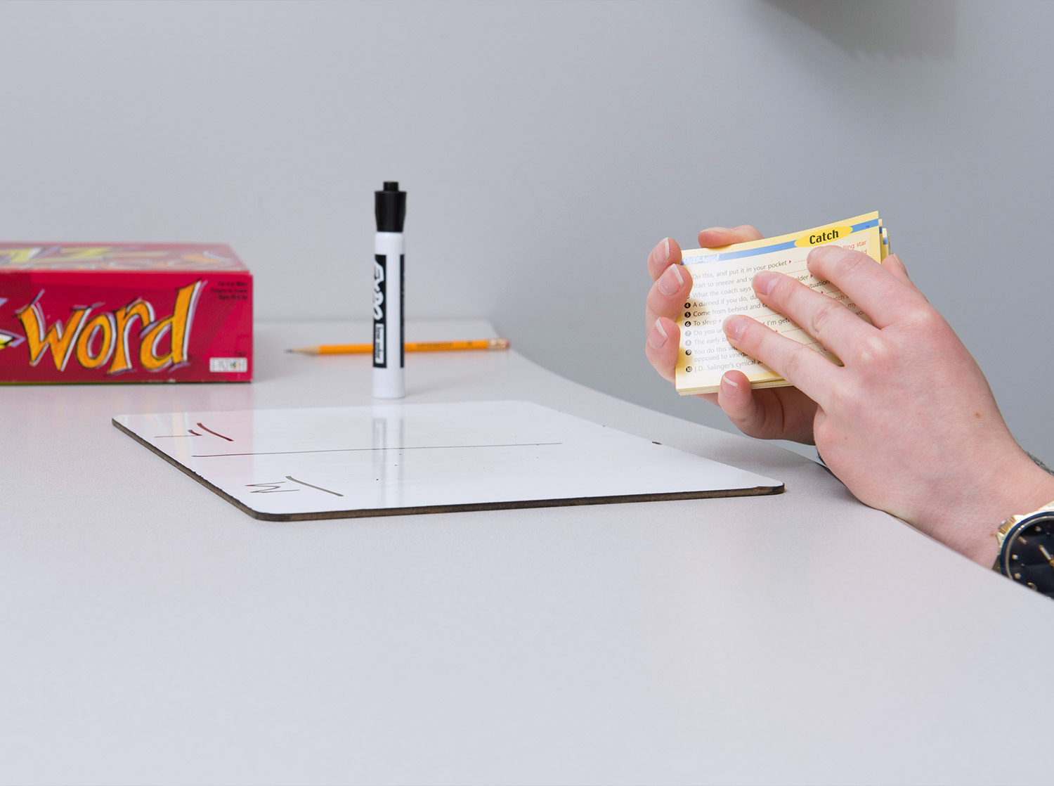 A student holds flash cards and a small whiteboard sits on a table