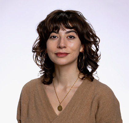 Headshot of Sophia Schlesinger, a young woman with short brown hair wearing a tan sweater and gold necklace