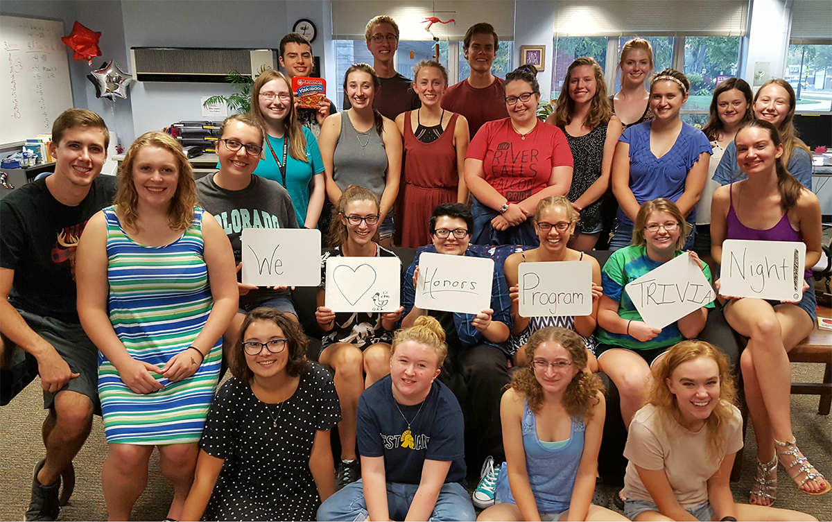 Honors Program students are gathered together and holding up signs that say We Love Honors Trivia Night