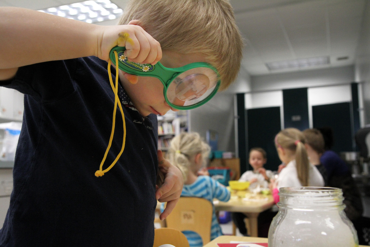 a young child uses a magnifying glass
