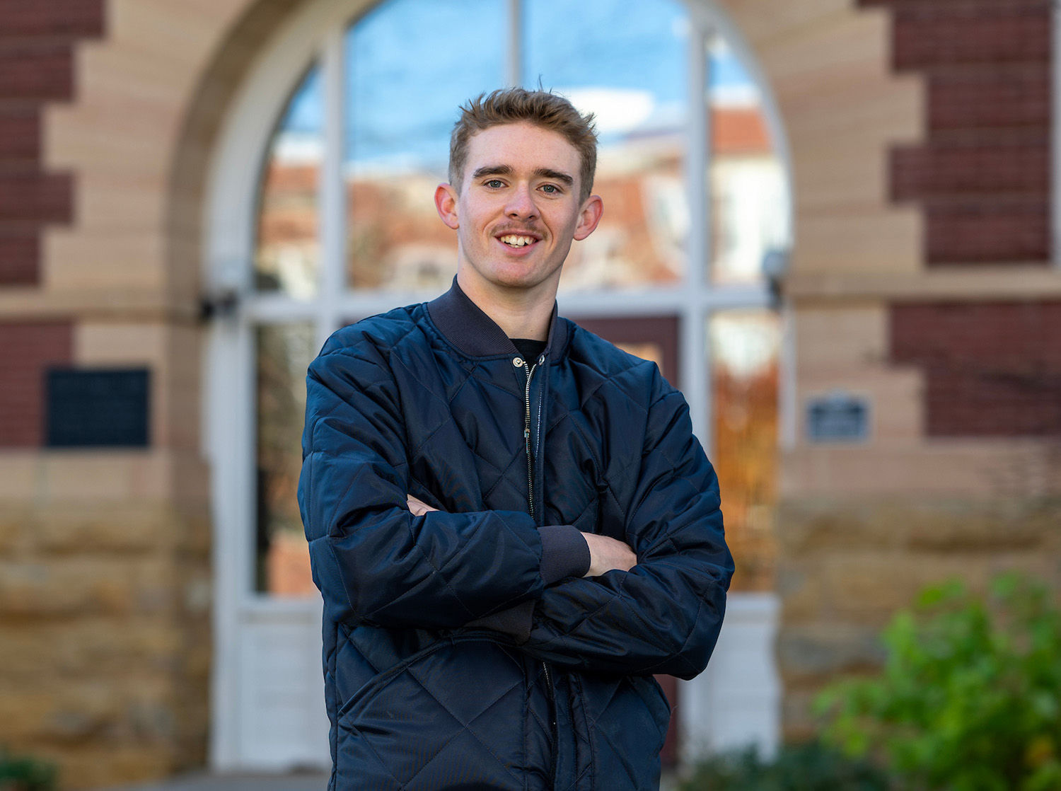Man in a blue jacket and jeans standing in front of South Hall