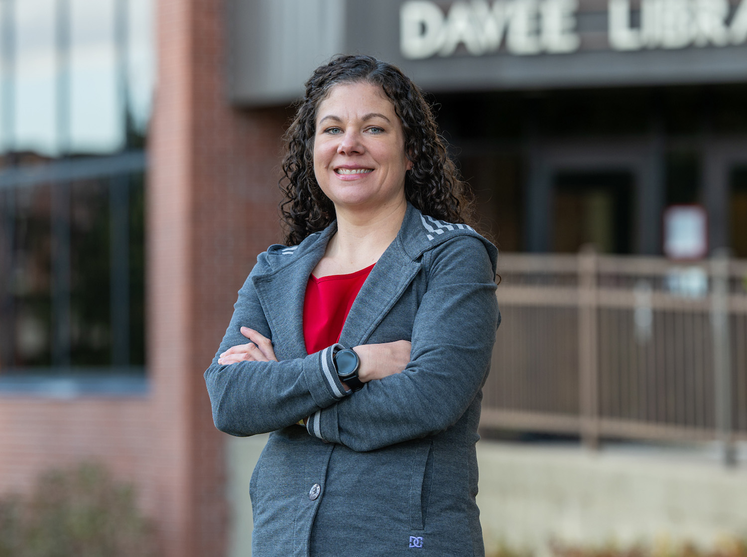 Woman in a red blouse and gray jacket standing in front of the Chalmer Davee Library