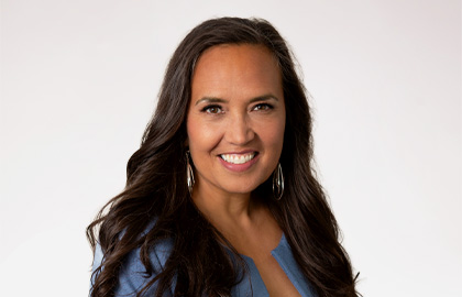 Headshot of Wendy Waiwaiole, a woman with long curled brown hair wearing a denim blue blouse