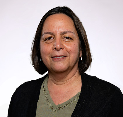 Headshot of Yoana Newman, a woman with short black hair wearing a green shirt and black cardigan