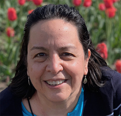 Headshot of Yoana Newman surrounded by bright red flowers