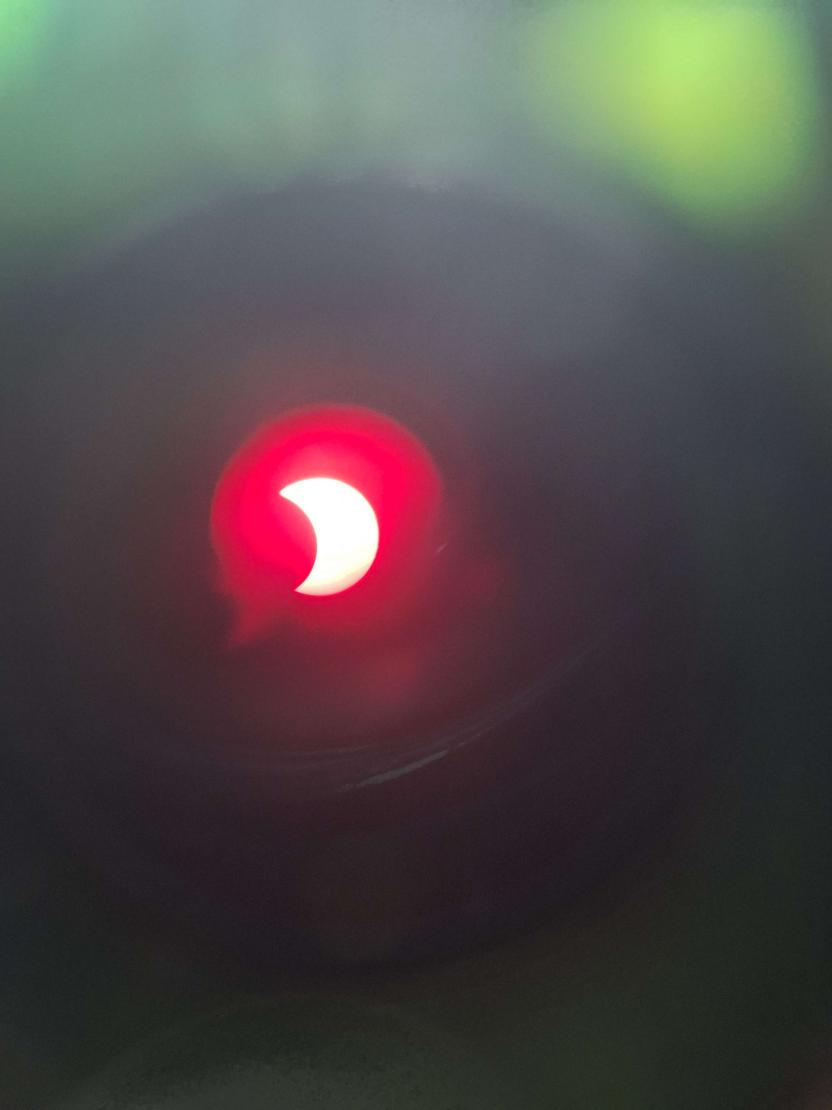 The partial eclipse shows a red sun through the telescope