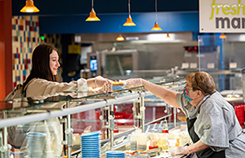 A student receives food from an employee at Riverside Commons