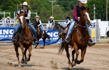 Two students on horseback ride around the arena to signal the start of the Falcon Frontier days