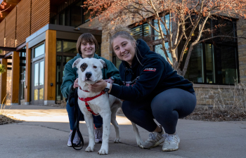 Two students and a dog pose for the camera outside of South Fork Suites