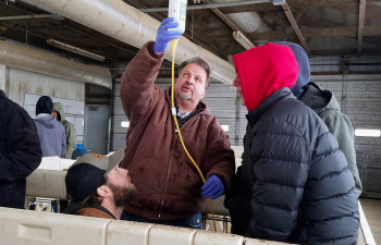 Professor Steve Kelm holds a bottle with a drip tube to allow medicine into the feeding bottle for a calf