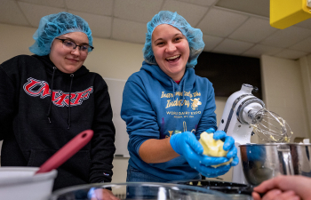 A student holds handmade butter in her hands during a food lab