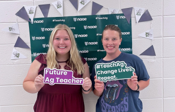 Two female students pose with signs saying "Future Ag Teacher"