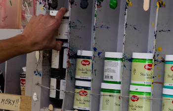 A students' hand reaches for a jar of paint