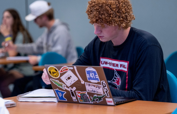 A male student works on his laptop during class