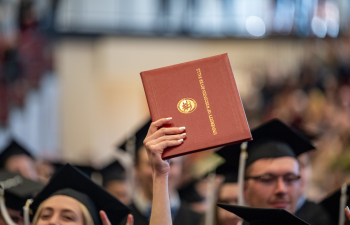 a graduate holds a diploma in the air