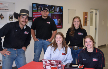 The Beef Management Team sits behind a table at an event