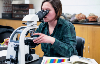 A student uses a microscope to study a test sample