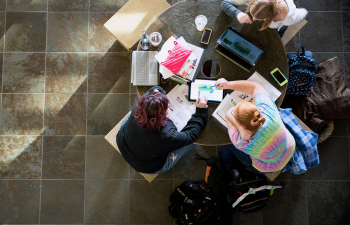 Three students sit at a round table comparing notes after class in the University Center
