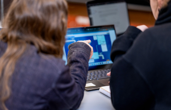 A professor points at information on a students laptop
