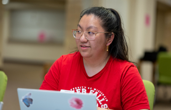 A female student works on their laptop during a marketing class