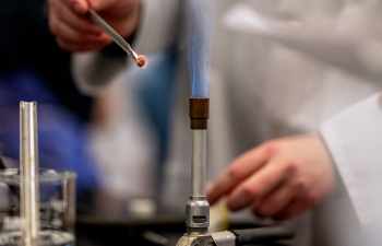 A student uses a Bunsen Burner to heat material during a lab exercise