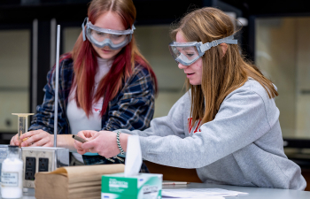 Two female students work on a lab exercise during class