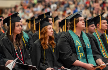 Graduates listen intently to the student speaker at commencement in Page Arena