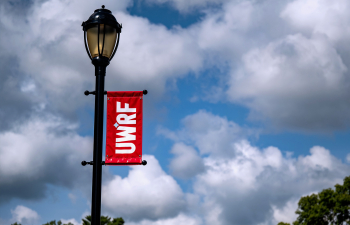 Looking up at a light post with the red UWRF banner hanging from it