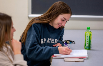 A female student takes notes during an economics class